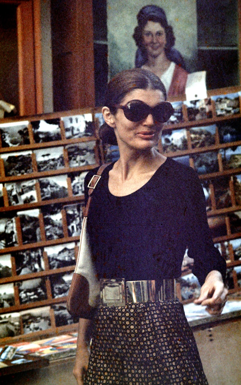 Jackie Onassis wears her signature oversized sunnies and Gucci bag with a black top and printed skir…