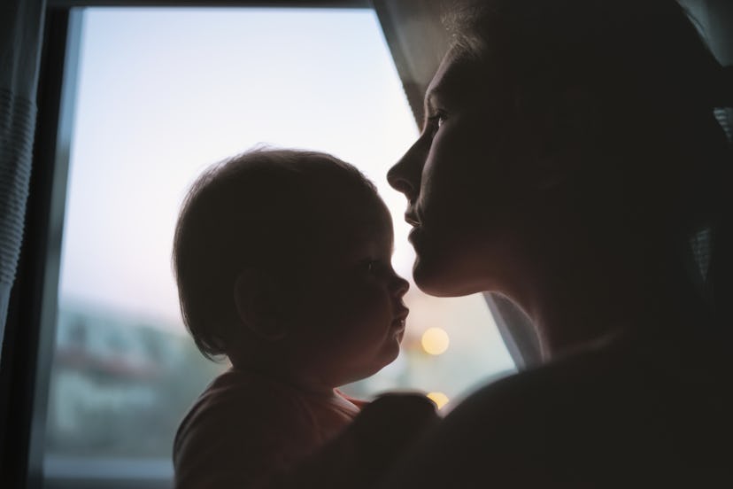 a mother and baby by a window in an article about intrusive thoughts postpartum