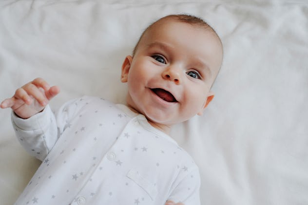 Goth baby names like Luna would fit this baby, smiling to camera and wearing star pajamas.