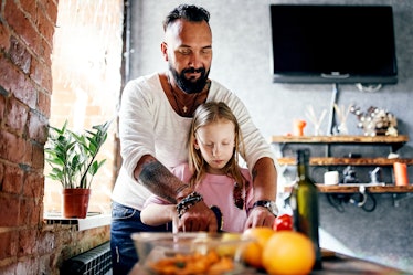 Dad and daughter spend time together in a grunge-style apartment and cook a salad together. A man of...