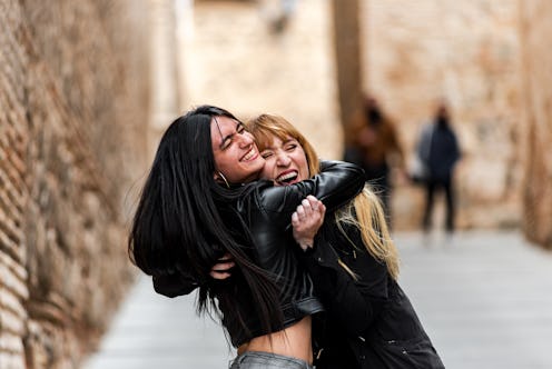 Blonde and brunette woman hugging each other happily. Concept of friendship and happiness.