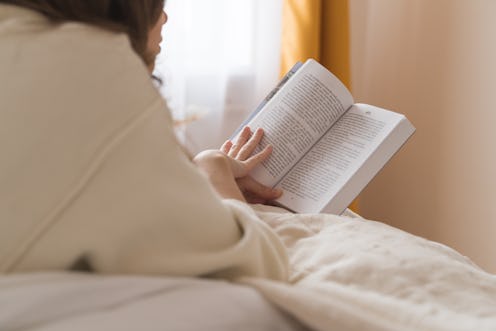 Young woman reading book and lying on the bed