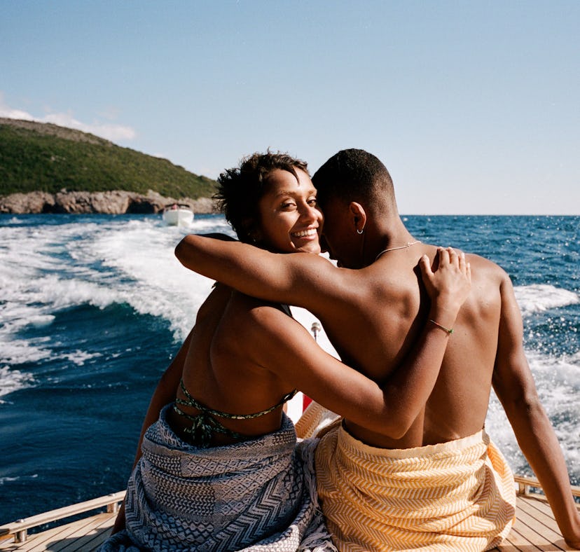 Portrait of smiling woman arm around with boyfriend on boat deck against sky during sunny day