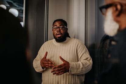 A man has a serious expression as he interrupts his onlookers. 