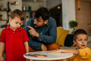 A young boy looks sad and down while his father corrects him for something he did wrong. Parenting c...