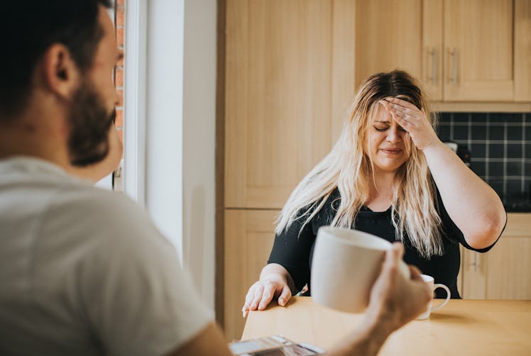 An upset and crying woman looks distressed as she has a serious conversation with a male who sits wi...