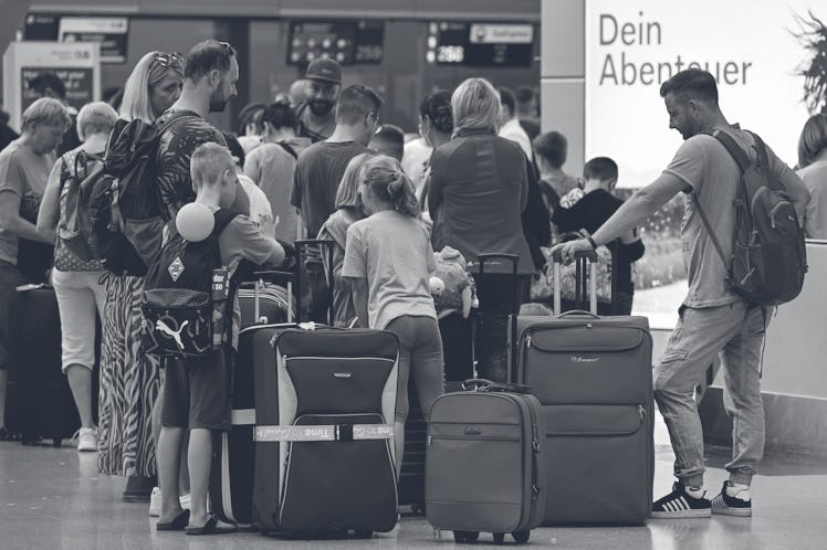A family and other passengers queue at the check-in counter at Duesseldorf International Airport (DU...