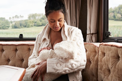 Young mother breastfeeding baby daughter while sitting in camper van, in an article about freeze dri...