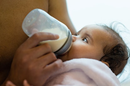 Man feeding his baby girl with a baby bottle in an article about freeze-dried breast milk