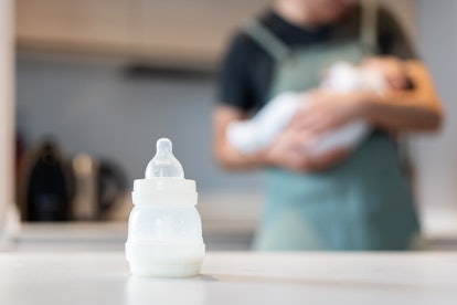 Dad hugging baby feeding maternal milk bottle in an article about freeze-dried breast milk.