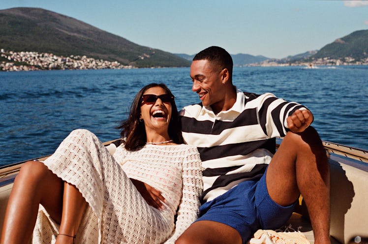 a young couple shares a laugh on a boat as they consider how their June 2023 horoscope will affect t...