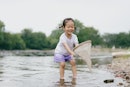 一个小女孩在一个流的水捕鱼的万博体育app安卓版下载网。她有马尾辫和年代……