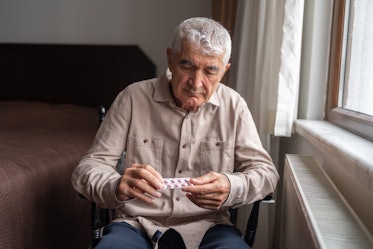 Senior Man Holding Pills In Hand At Home