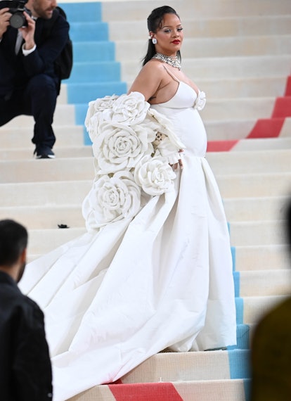 Rihanna wears a white dress and a white rose-covered cape to the Met Gala 2023. 