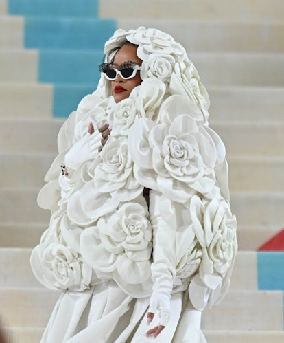 Rihanna wears a white dress and a white rose-covered cape to the Met Gala 2023. 