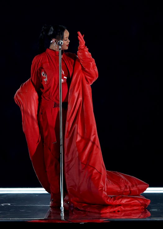 Rihanna wears a red cape and breastplate during the Apple Music Super Bowl LVII Halftime Show. 