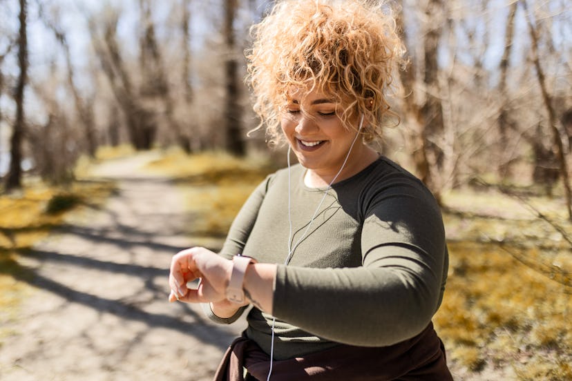 Young overweight woman runner looking at smart