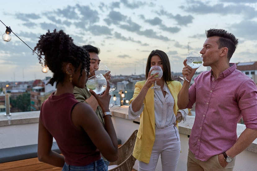 Group of multi-ethnic people having drinks while enjoying together in a terrace. Friendship concept.