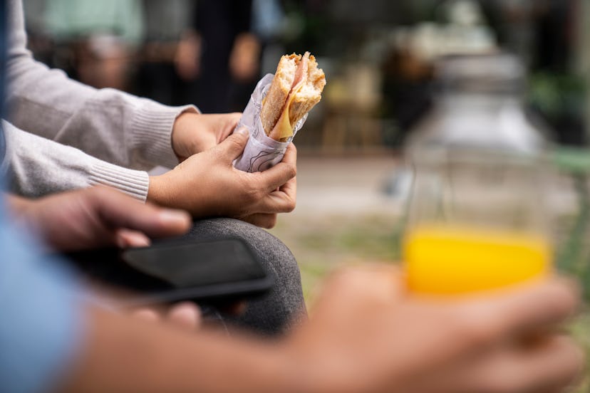 Close-up shot of an out of focus male hand holding a bottle of orange juice and a pair of hands hold...