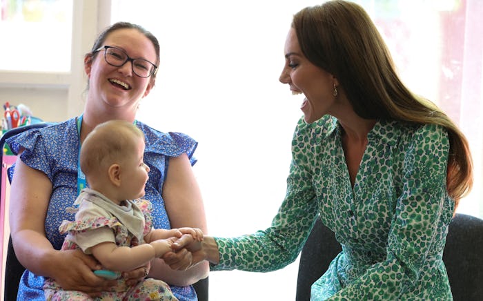 Britain's Catherine, Princess of Wales holds the hand of a baby as she meets with health visitors at...