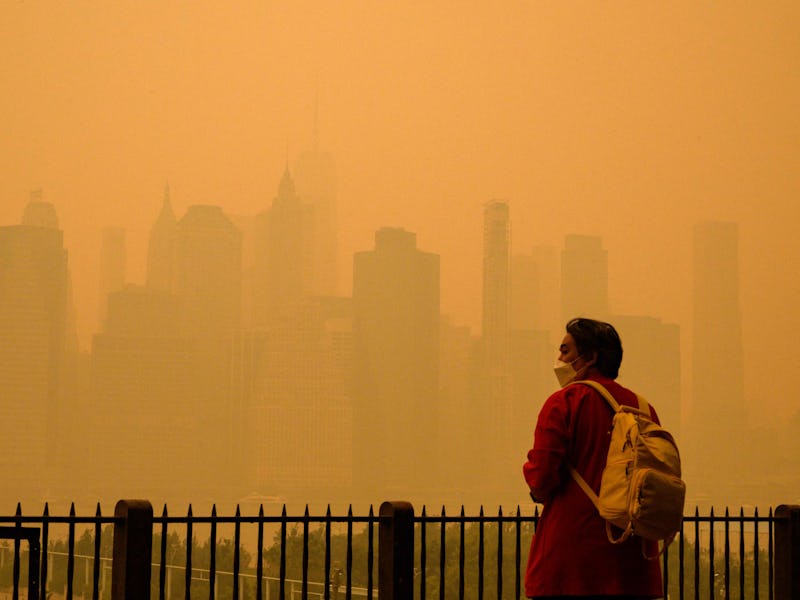 A person wears a face mask as smoke from wildfires in Canada cause hazy conditions in New York City ...
