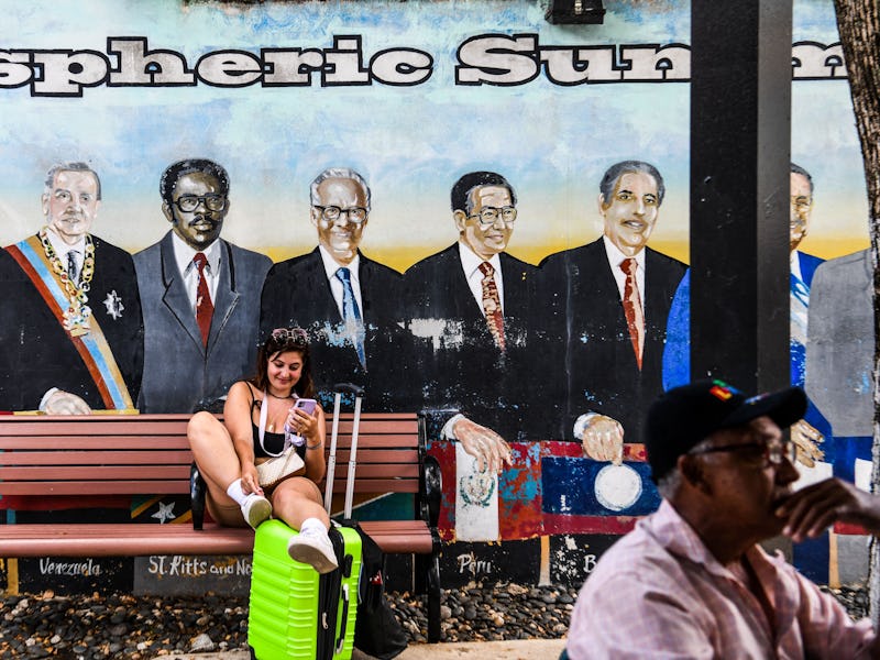 A woman sits on a bench near a mural of South American leaders at Domino Park, located in a Cuban ne...