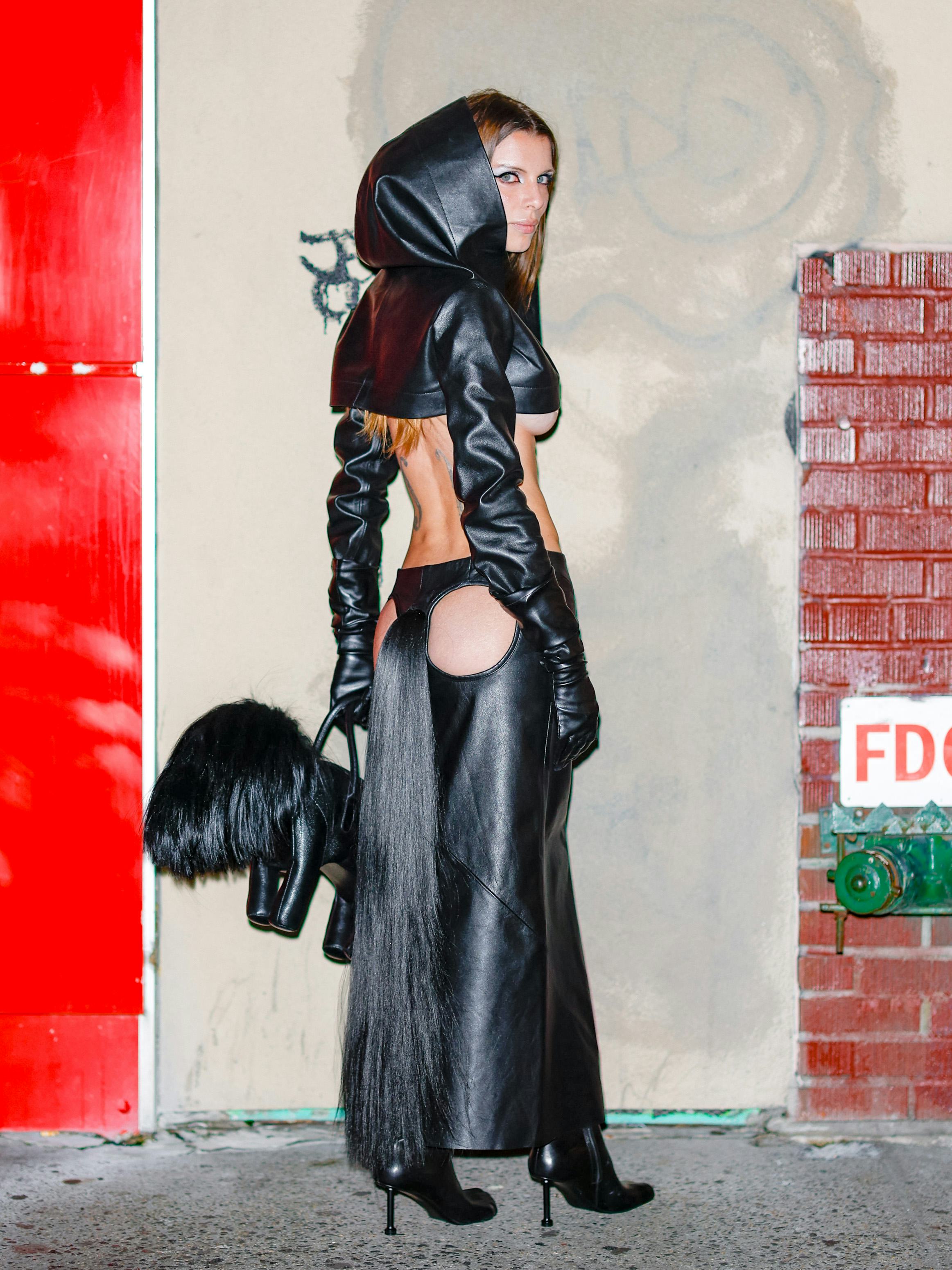 Julia Fox wears a hooded crop top and a skirt with butt cut-outs and a faux horsetail.