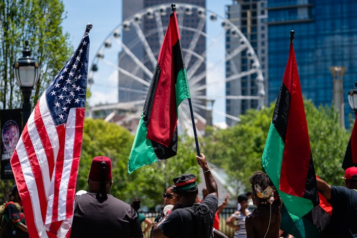 ATLANTA, GA - JUNE 18: People raise American and Pan-African flags while marching in the Juneteenth ...