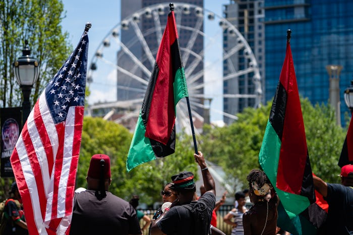 ATLANTA, GA - JUNE 18: People raise American and Pan-African flags while marching in the Juneteenth ...