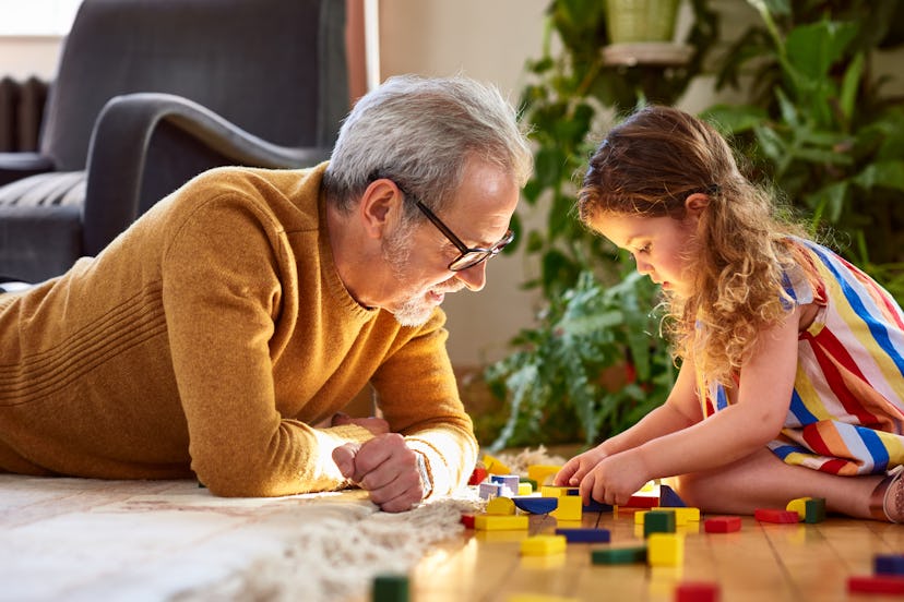 man lying on floor playing with little girl, in a list of ideas for father's day cards for Grandpa