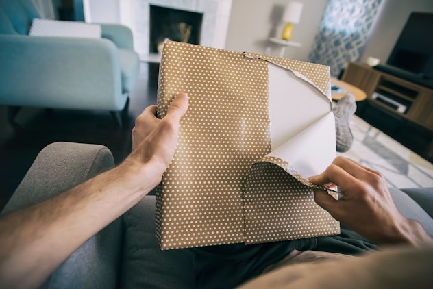 man opening present in article about whether or not you should celebrate soon to be dads on father's...