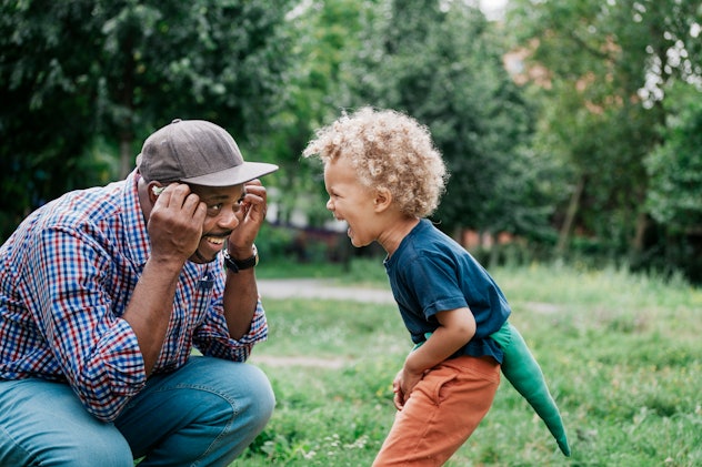 A young boy laughing at his playful grandfather while hanging out for the day at the park together. ...