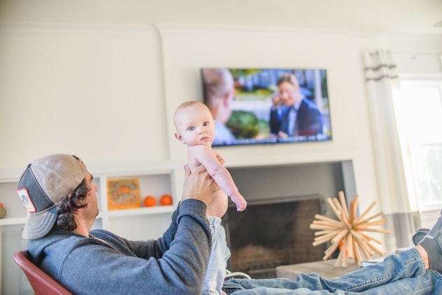 dad holding newborn baby watching tv in article about what not to say to expectant dads on father's ...