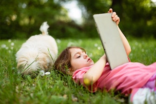 A little girls looks at a tablet instead of playing outside with her dog. Anti-dopamine parenting is...