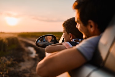 Father and son looking out of their car at a sunset.