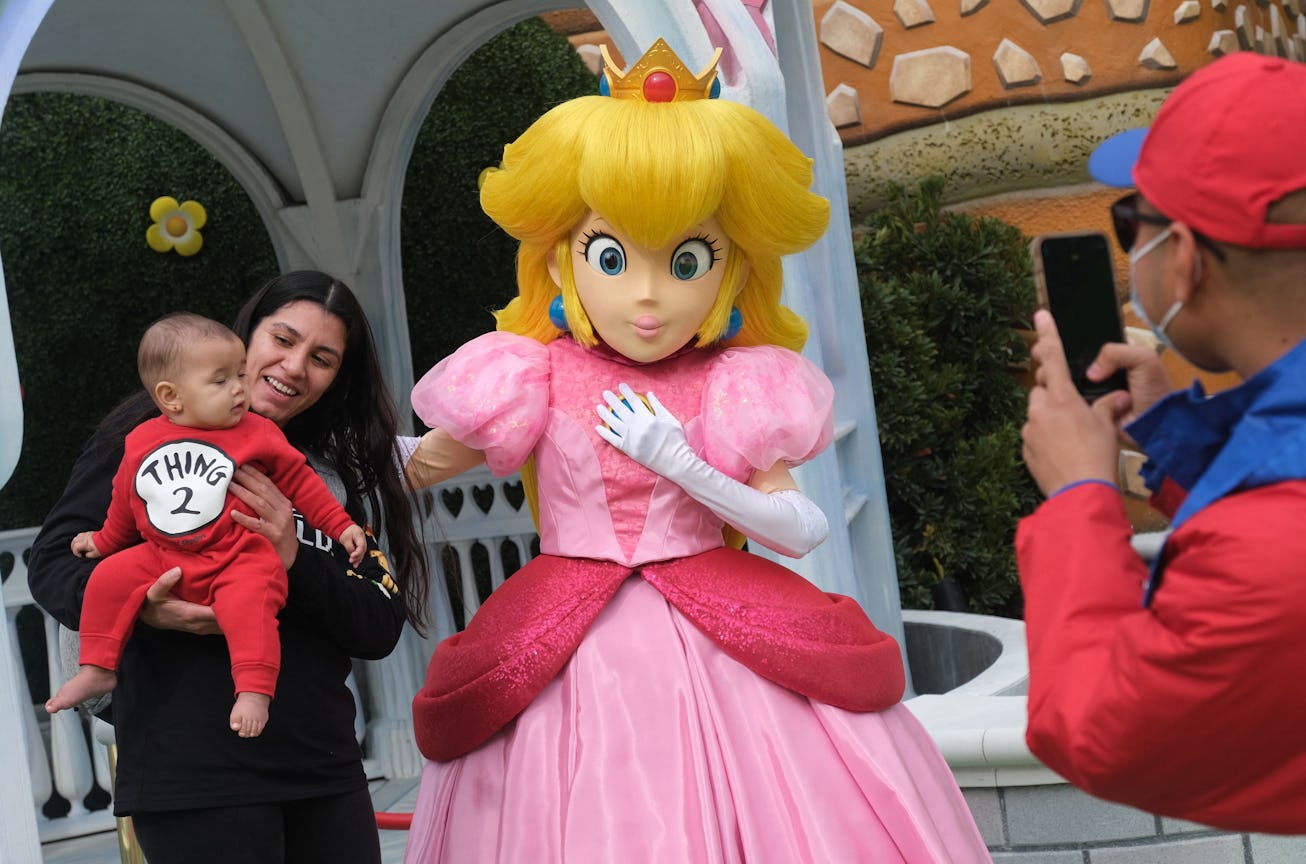 Guests take pictures with Princess Peach during a preview of Super Nintendo World at Universal Studi...