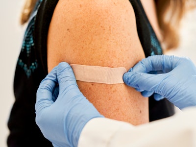 Doctor applying band-aid to his patients after receiving the third dose of vaccine for immunization