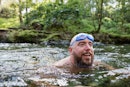 Man wild swimming in the Lake District, North East of England. He is in a river, enjoying time outdo...