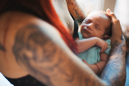 woman with tattoos holding newborn baby in article about emo-inspired baby names
