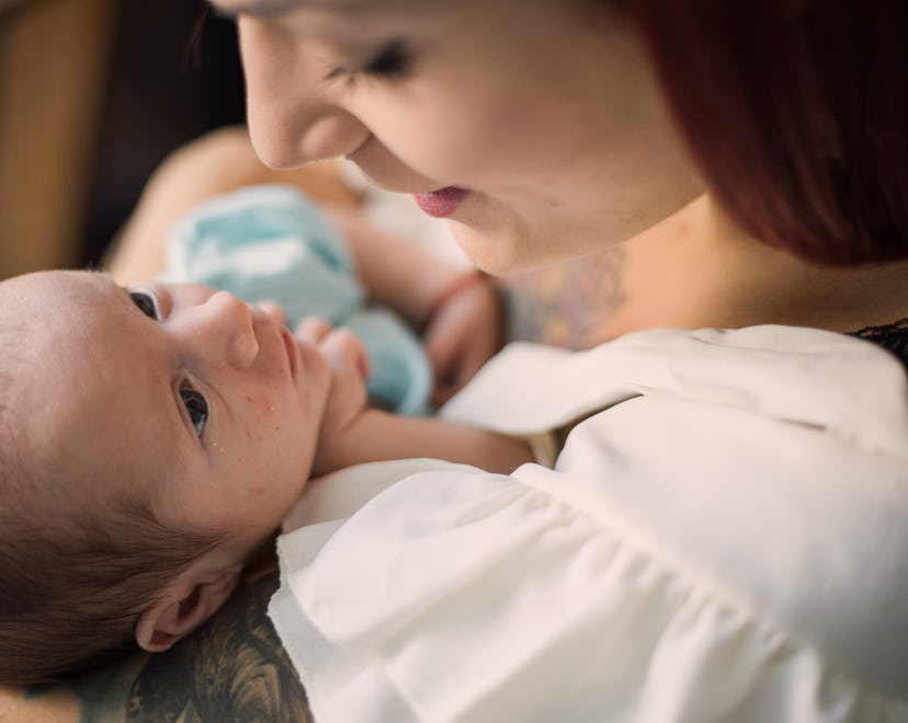 Mom holding baby on left side and looking down at him lovingly.