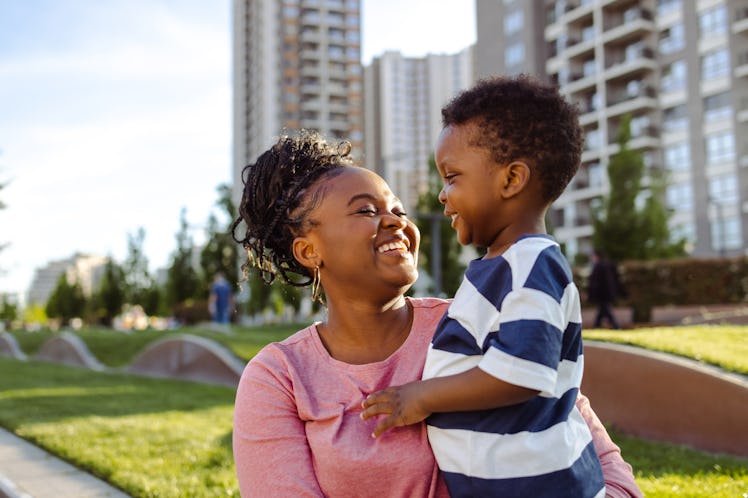 Cheerful mother and son enjoying in the park on the nice sunny afternoon. She is wearing a pink shir...