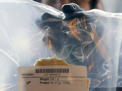 A technician holds a lab-grown chicken meat in a sealed bag at the food-tech startup SuperMeat in th...