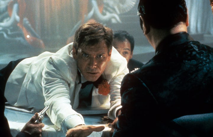 Harrison Ford lunges across a table in a scene from the film 'Indiana Jones And The Temple Of Doom',...