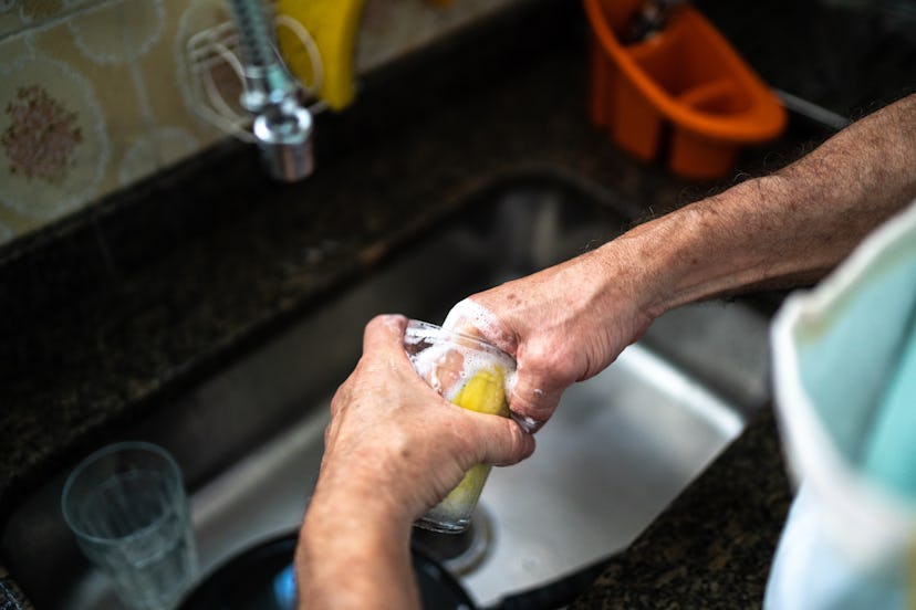 Close-up of a man washing a glass in kitchen sink at home
