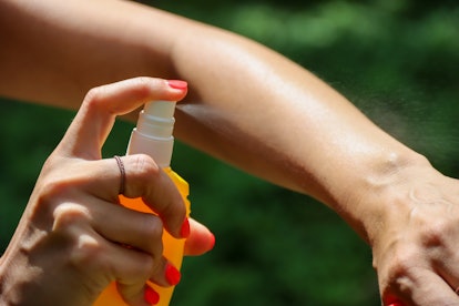 Person sprays arm with bug spray, in a story about pregnancy safe bug sprays.