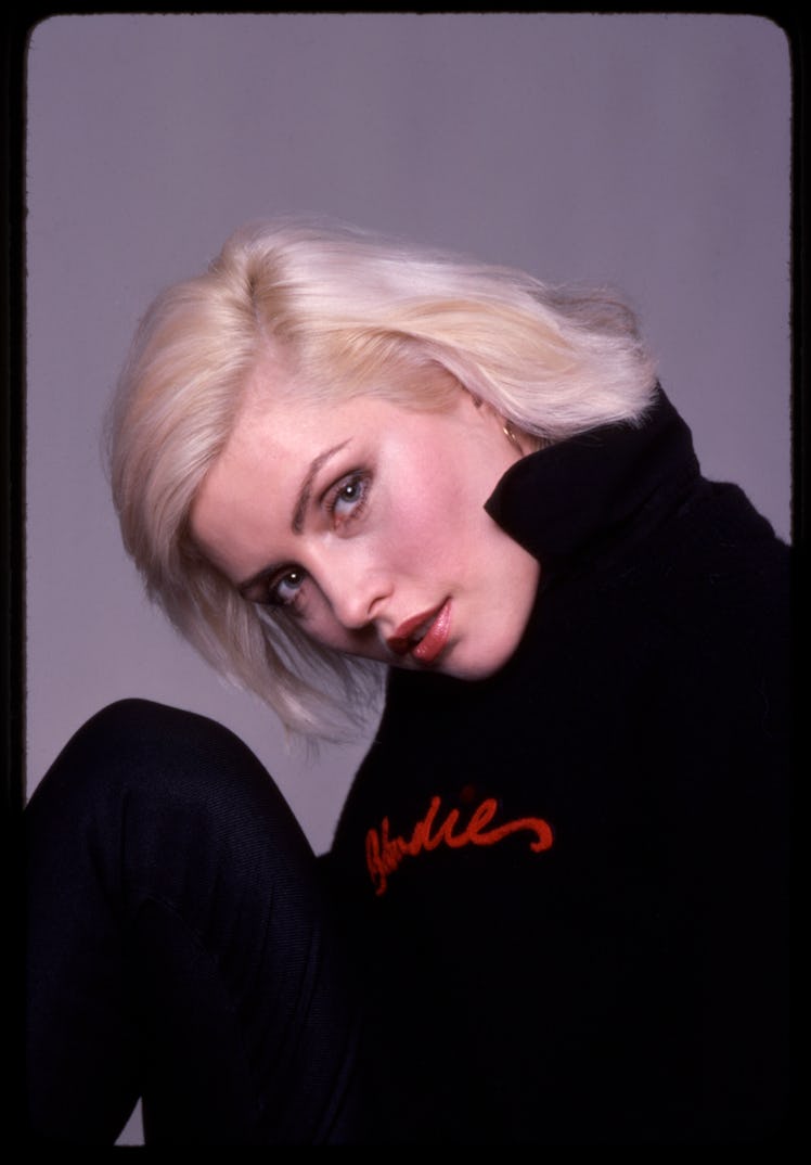 Portrait of Debbie Harry, of the band Blondie, as she poses against a grey backdrop.