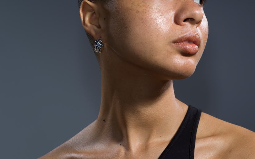 Headshot of model with darker skin wearing asymmetrical top looking to her left