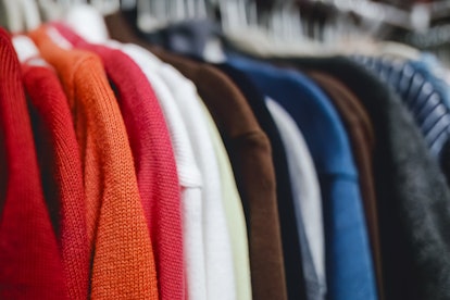 Close-up of a colorful variety of women's long-sleeved knit tops hanging in closet