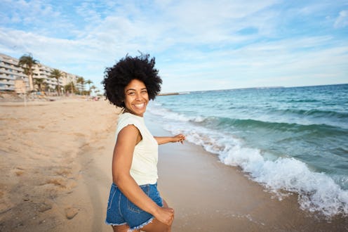 Cheetful african woman turning to smile at camera while running along the beach