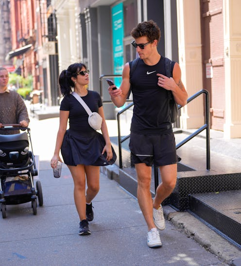Camila Cabello and Shawn Mendes wear matching black gym outfits. Cabello wears a shirt and pleated t...